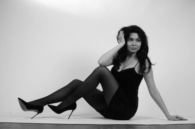 Siyah elbiseli güzel bir kadın stüdyoda poz veriyor, siyah beyaz. 