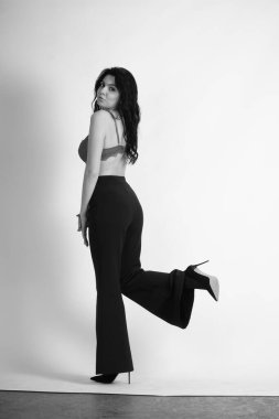 Siyah elbiseli güzel bir kadının siyah beyaz portresi stüdyoda poz veriyor.