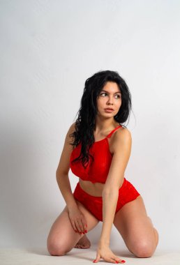 Beyaz odadaki kameraya kırmızı iç çamaşırlı çekici, genç, esmer manken.