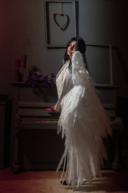Kırmızı iç çamaşırlı ve beyaz ceketli güzel seksi bir kız. Stüdyoda kameraya kanatlı poz veriyor. 