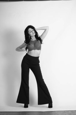 Siyah elbiseli güzel bir kadının siyah beyaz portresi stüdyoda poz veriyor.