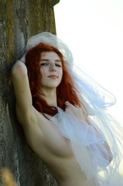 Seksi, çıplak kızıl saçlı, yaz tatilinin tadını çıkarıyor. Denizde poz veren güzel çıplak genç bir kadın.. 