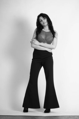 Siyah elbiseli güzel bir kadının siyah beyaz portresi stüdyoda poz veriyor.