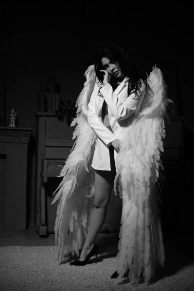 Beautiful sexy girl in lingerie and jacket with wings posing at the camera in the studio, Black and white photo