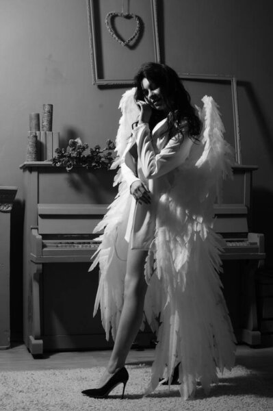 Beautiful sexy girl in lingerie and jacket with wings posing at the camera in the studio, Black and white photo
