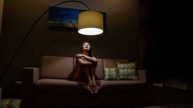 Güzel, seksi esmer kadın, odadaki kanepede poz veriyor.