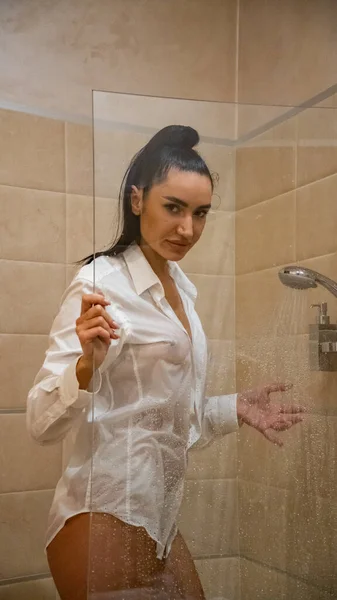 漂亮的年轻女子赤身裸体 只穿着一件湿透了的男式衬衫 在浴室里摆姿势 — 图库照片