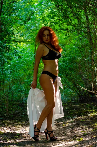 穿着黑色女士内衣的年轻貌美的女子在绿色的夏季森林里摆姿势 — 图库照片