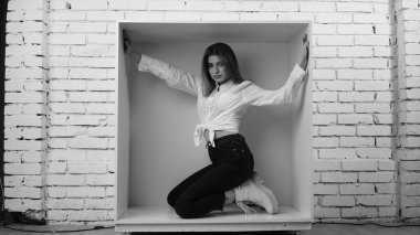 Stüdyoda beyaz gömlekli seksi ve seksi bir kadının beyaz bir duvara poz verdiği bir fotoğraf..  