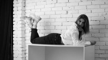 Stüdyoda uzun saçlı, uzun saçlı, siyah beyaz bir kadın poz veriyor..  