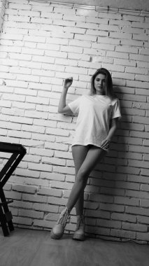 Stüdyoda sandalyenin yanında uzun saçlı, siyah beyaz bir kadın poz veriyor..  