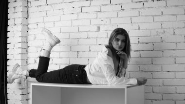 Stüdyoda uzun saçlı, uzun saçlı, siyah beyaz bir kadın poz veriyor..  