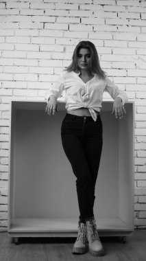 Stüdyoda uzun saçlı, uzun saçlı, siyah beyaz bir kadın poz veriyor..  