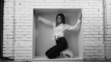 Stüdyoda beyaz gömlekli seksi ve seksi bir kadının beyaz bir duvara poz verdiği bir fotoğraf..  