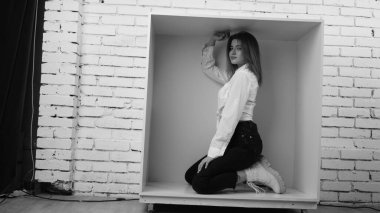 Stüdyoda beyaz gömlekli seksi ve seksi bir kadının beyaz bir duvara poz verdiği bir fotoğraf..  