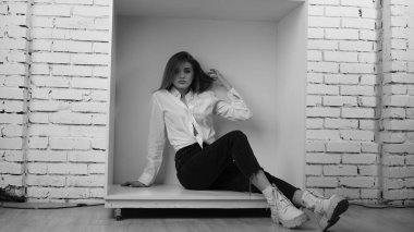 Stüdyoda uzun saçlı, uzun saçlı, siyah beyaz bir kadın poz veriyor..  