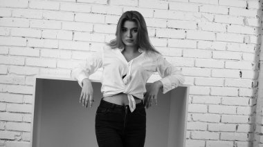 Stüdyoda uzun saçlı, uzun saçlı, siyah beyaz bir kadın poz veriyor..  