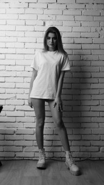 Stüdyoda sandalyenin yanında uzun saçlı, siyah beyaz bir kadın poz veriyor..  