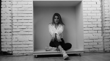 Stüdyoda uzun saçlı, uzun saçlı, siyah beyaz bir kadın poz veriyor..  