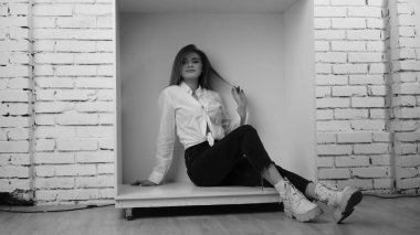 Stüdyoda uzun saçlı, uzun saçlı, siyah beyaz bir kadın poz veriyor..  