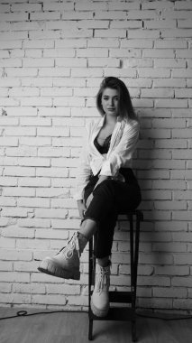 Beyaz tişörtlü, siyah beyaz saçlı, güzel ve seksi bir kadının stüdyoda beyaz bir duvara poz verdiği siyah beyaz bir fotoğraf..  