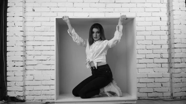 在工作室里 年轻美丽的性感性感女人身穿白衬衫 靠着一面白砖墙摆姿势 — 图库照片