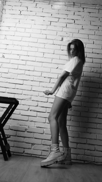 Stüdyoda sandalyenin yanında uzun saçlı, siyah beyaz bir kadın poz veriyor..  