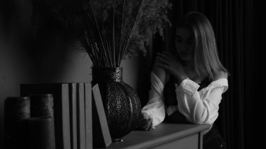 Stüdyoda piyanonun yanında uzun saçlı, beyaz gömlekli, güzel, şehvetli ve seksi bir kadının siyah beyaz fotoğrafı..  