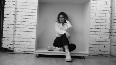 Stüdyoda uzun saçlı, uzun saçlı, siyah beyaz bir kadın poz veriyor..  