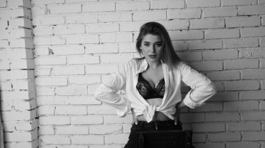 Beyaz tişörtlü, siyah beyaz saçlı, güzel ve seksi bir kadının stüdyoda beyaz bir duvara poz verdiği siyah beyaz bir fotoğraf..  