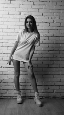 Stüdyoda sandalyenin yanında uzun saçlı, siyah beyaz bir kadın poz veriyor..  