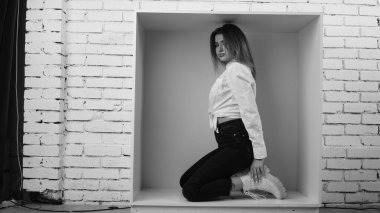 Stüdyoda beyaz gömlekli seksi ve seksi bir kadının beyaz bir duvara poz verdiği bir fotoğraf..  