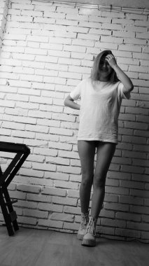 Stüdyoda sandalyenin yanında uzun saçlı, siyah beyaz bir kadın poz veriyor..  