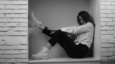 Stüdyoda uzun saçlı, uzun saçlı, siyah beyaz bir kadın poz veriyor..  