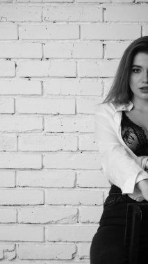 Beyaz tişörtlü, siyah beyaz saçlı, güzel ve seksi bir kadının stüdyoda beyaz bir duvara poz verdiği siyah beyaz bir fotoğraf..  