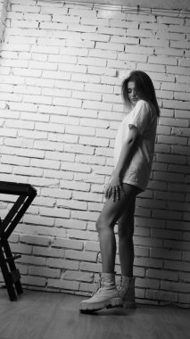 Stüdyoda sandalyenin yanında uzun saçlı, siyah beyaz bir kadın poz veriyor..  