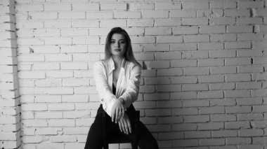 Beyaz tişörtlü, siyah beyaz saçlı, güzel ve seksi bir kadının stüdyoda beyaz bir duvara poz verdiği siyah beyaz bir fotoğraf..  