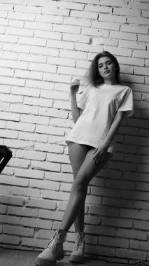 Stüdyoda sandalyenin yanında uzun saçlı, siyah beyaz bir kadın poz veriyor..  