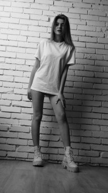 Stüdyoda sandalyenin yanında uzun saçlı, siyah beyaz bir kadın poz veriyor..  