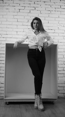 Stüdyoda uzun saçlı, uzun saçlı, siyah beyaz bir kadın poz veriyor..  