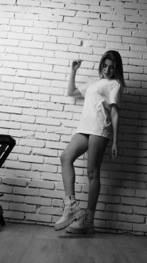 Stüdyoda sandalyenin yanında uzun saçlı, siyah beyaz bir kadın poz veriyor..  