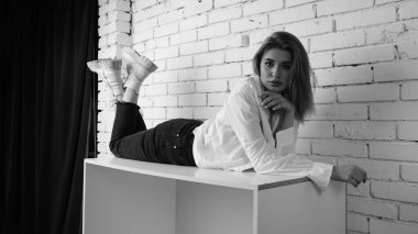 Stüdyoda uzun saçlı, uzun saçlı, siyah beyaz bir kadın poz veriyor..  