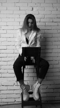 Beyaz tişörtlü, siyah beyaz saçlı, güzel ve seksi bir kadının stüdyoda beyaz bir duvara poz verdiği siyah beyaz bir fotoğraf..  