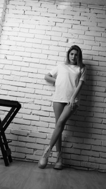 Stüdyoda sandalyenin yanında uzun saçlı, siyah beyaz bir kadın poz veriyor..  