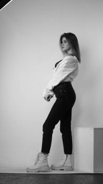 Stüdyoda uzun saçlı, uzun saçlı, siyah beyaz bir kadın poz veriyor..  