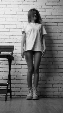 Stüdyoda sandalyenin yanında uzun saçlı, siyah beyaz bir kadın poz veriyor..  