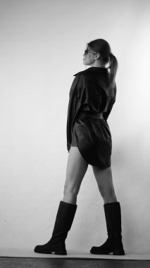 Siyah gömlekli ve güneş gözlüklü genç bir kadının stüdyoda poz verirken çekilmiş siyah beyaz bir fotoğrafı..  