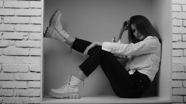 Stüdyoda uzun saçlı, uzun saçlı, siyah beyaz bir kadın poz veriyor..  