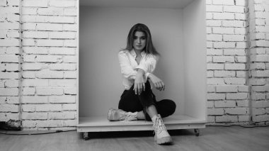 Stüdyoda uzun saçlı, uzun saçlı, siyah beyaz bir kadın poz veriyor..  