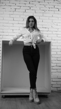 Stüdyoda uzun saçlı, uzun saçlı, siyah beyaz bir kadın poz veriyor..  